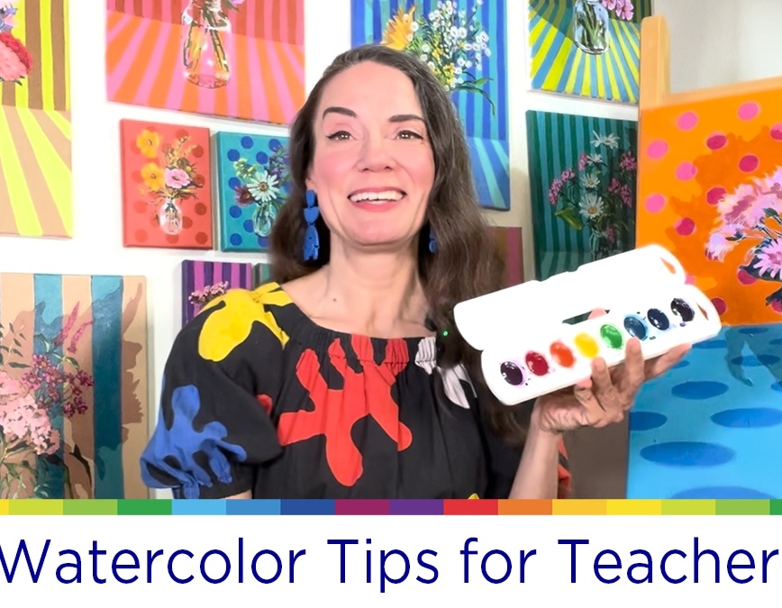 Smiling woman sharing watercolor tips in an artistic studio setting.